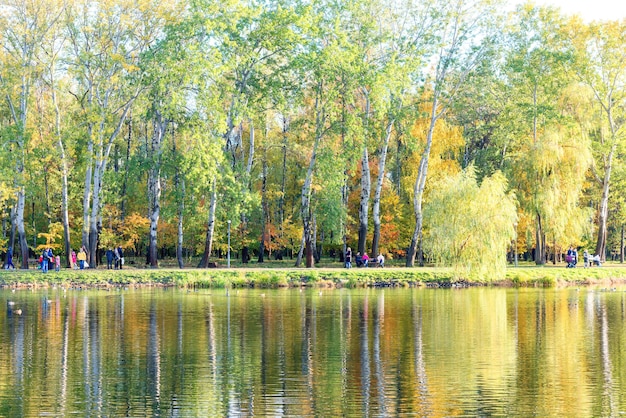 See mit Vögeln im herbstlichen Stadtpark mit wandernden Menschen