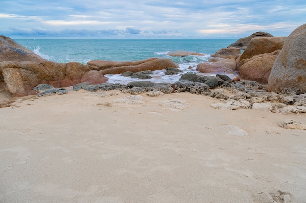See- und Felsensteine ​​auf dem Strand mit Hintergrund des Sandes und des blauen Himmels