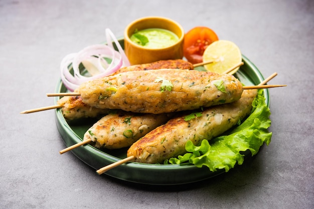 Seekh Kabab aus gehacktem Hühnchen oder Hammel-Keema, serviert mit grünem Chutney und Salat