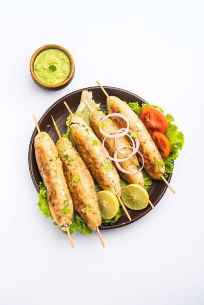 Seekh Kabab aus gehacktem Hühnchen oder Hammel-Keema, serviert mit grünem Chutney und Salat