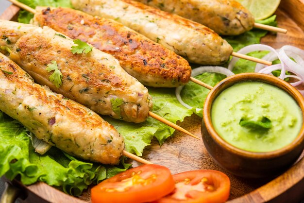 Seekh Kabab aus gehacktem Hühnchen oder Hammel-Keema, serviert mit grünem Chutney und Salat