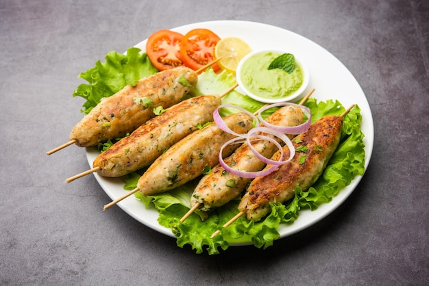 Seekh Kabab aus gehacktem Hühnchen oder Hammel-Keema, serviert mit grünem Chutney und Salat