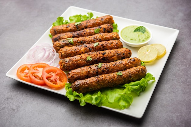 Seekh Kabab aus gehacktem Hühnchen oder Hammel-Keema, serviert mit grünem Chutney und Salat