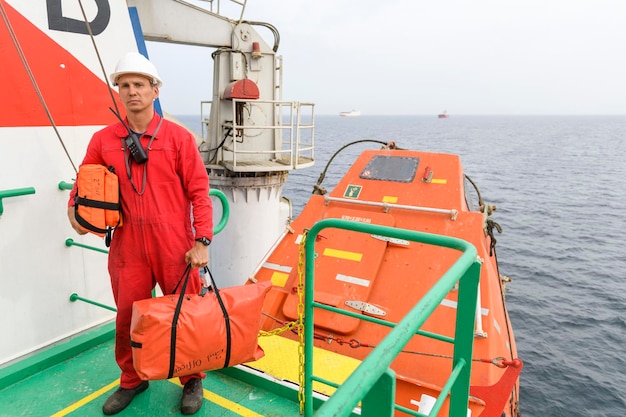 Seemann mit Rettungsweste mit VHF-Radio auf der Muster-Station Verlassen Sie die Schiffsausübung Freifallboot