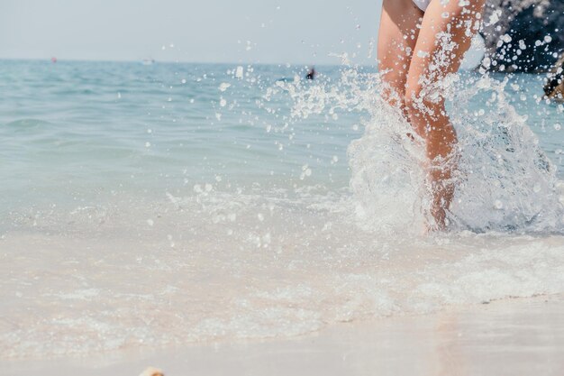 Seestrandreisefrau, die auf Sandstrand geht und Fußabdrücke in den weiblichen Beinen des weißen Sandes hinterlässt