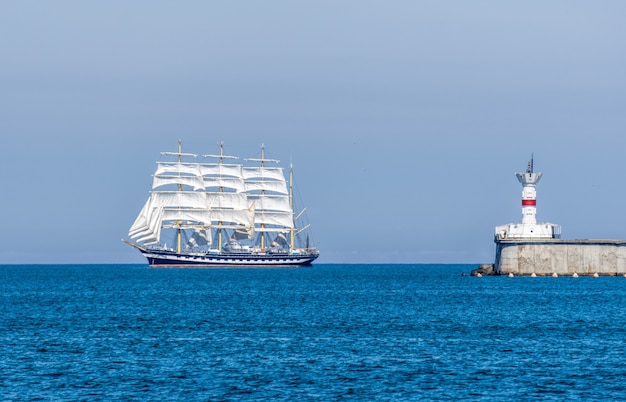 Seestück mit weißem Segelschiff und Leuchtturm