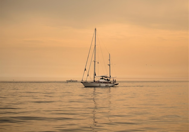 Segelboot fährt bei Sonnenuntergang auf dem Meer gegen den Himmel