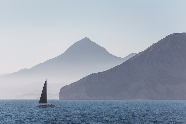 Segelboot im Meer vor dem Hintergrund schöner großer Berge, luxuriöses Sommerabenteuer, aktiver Urlaub im Mittelmeer.