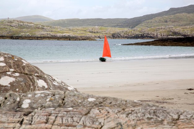 Segelboot und Felsen am Strand von Glassillaun, Connemara, Irland