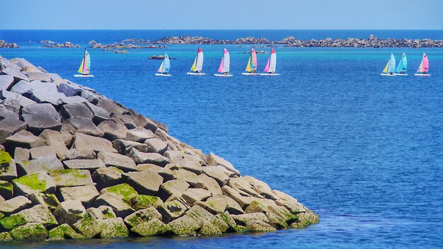 Foto segelboote auf see mit felsen im vordergrund