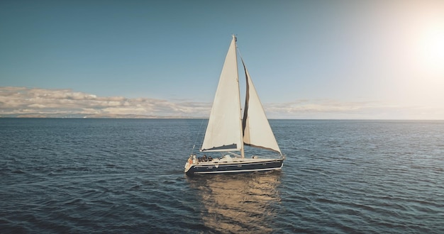 Foto segelyacht-rennen bei sonnenlicht in der luft segeln auf ruhiger meereslandschaft auf offenem meer boot großes weißes segel