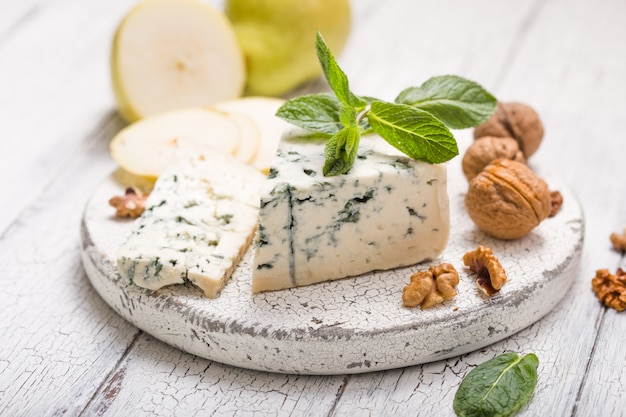 Segmento de queso moho azul - Gorgonzola con pera y nueces sobre tabla de madera.