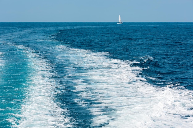 Seguimiento en la superficie del agua en el mar y velero en el lejano