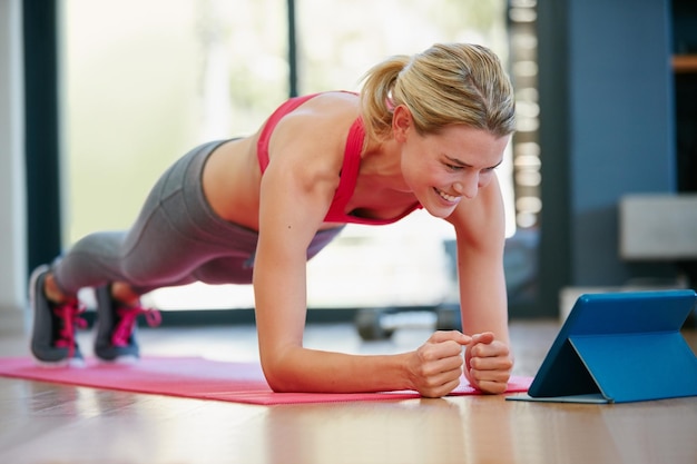 Seguindo alguns tutoriais de fitness online Foto de uma jovem esportiva malhando em casa
