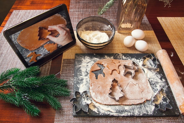 Seguir la receta en una tableta digital: cortar la masa con un molde para hacer pan de jengibre navideño.