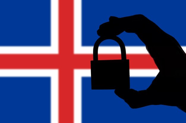 Segurança da Islândia Silhueta de mão segurando um cadeado sobre a bandeira nacional