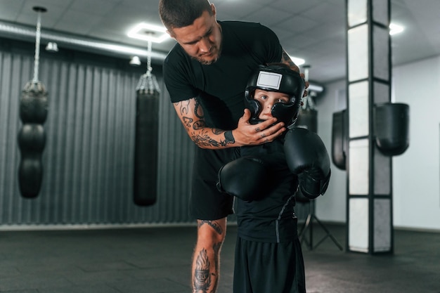 Segurança do treinador principal está ensinando técnicas de box para meninos dentro de casa