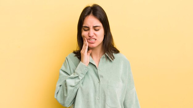 Segurando a bochecha e sofrendo dor de dente dolorosa, sentindo-se doente, miserável e infeliz, procurando um dentista