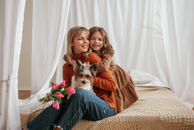 segurando flores para o feriado do dia das mães abraçando com o cachorro pai com a filha em casa