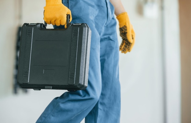 Segurando o caso Jovem trabalhando de uniforme na construção durante o dia