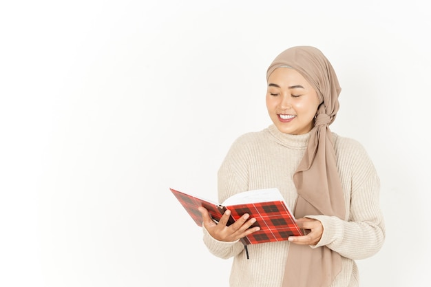 Segurando o livro de uma bela mulher asiática usando um hijab isolado no fundo branco