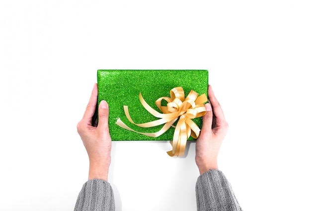 Segurando o presente de natal com papel de embrulho de glitter verde e fita de ouro