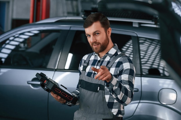 Segurando o tablet O homem de uniforme está trabalhando no salão de automóveis