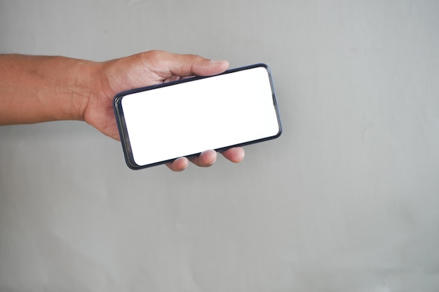 Foto segurando o telefone inteligente com tela vazia em fundo cinza
