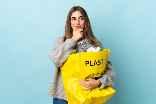 Segurando uma sacola cheia de garrafas plásticas para reciclar, rindo azul isolado