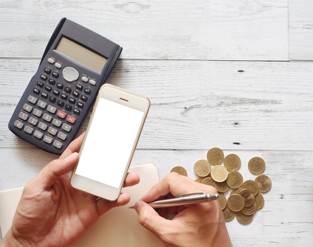 Segure a tela branca do celular usando calculadora com caneta de cacto no conceito de negócio da vista de cima da mesa