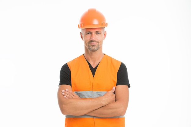 La seguridad es el punto principal. Hombre casco protector y fondo blanco uniforme. Cámara de mirada confiada del constructor del trabajador. Concepto de equipo de protección. Constructor de pecho de manos cruzadas. Constructor guapo fuerte.