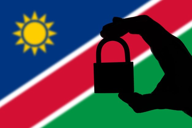 Seguridad de Namibia Silueta de mano sosteniendo un candado sobre bandera nacional