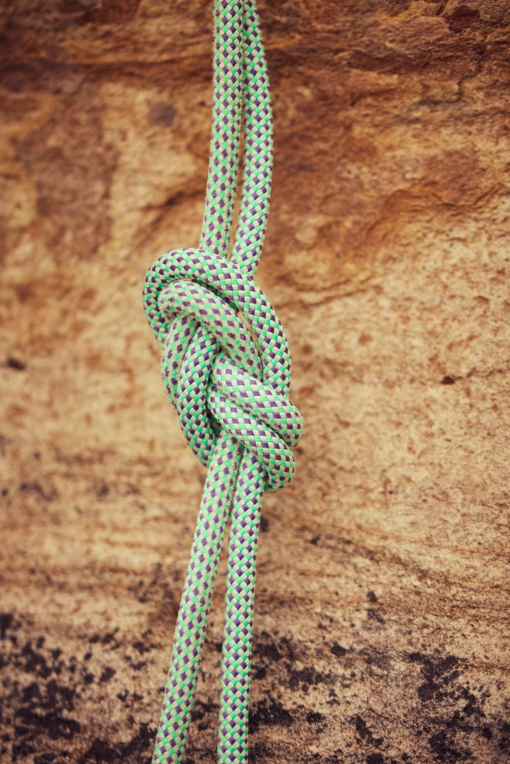 Foto seguridad y nudo de cuerda para escalar montañas para ayudar en el exterior o en el exterior, fuerte desafío de roca, riesgo de caída, peligro, ejercicio físico y equipo de entrenamiento para entrenamiento o aventura en la pared.