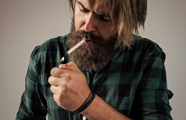 Seguridad de la salud y adicción apuesto hombre brutal hombre barbudo fumando cigarrillo hábito brutal hipster con bigote modelo de moda usar ropa casual estándar de belleza masculina que se ve tan de moda