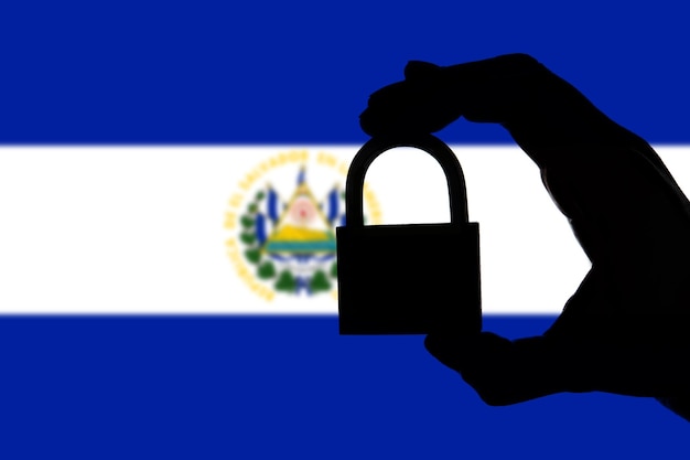 Foto seguridad de el salvador silueta de mano sosteniendo un candado sobre bandera nacional