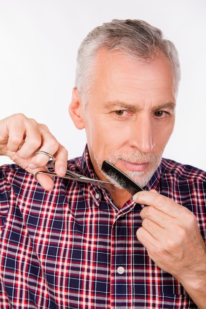 Seguro de anciano cortándose la barba