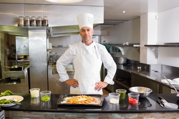 Seguro chef masculino con comida cocinada en la cocina