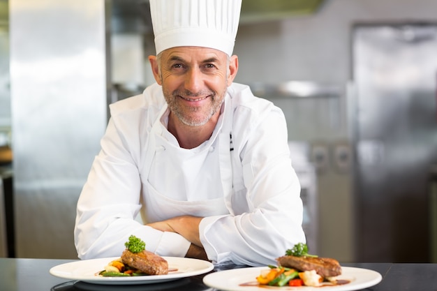 Seguro chef masculino con comida cocinada en la cocina