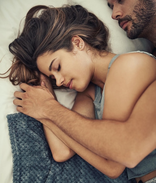 Foto seguro em seus braços foto de alto ângulo de um jovem casal afetuoso dormindo em sua cama