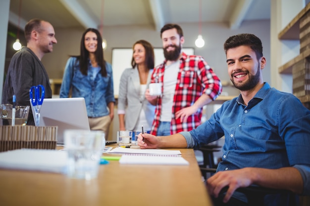 Seguro empresario creativo con colegas de pie junto a la mesa