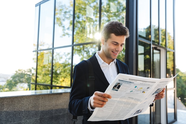 Seguro empresario leyendo el periódico mientras está de pie al aire libre