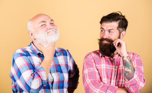 Seguro y guapo padre e hijo familia jóvenes vs vejez comparar jubilación barbería y peluquería dos hombres barbudos senior y hombre maduro cuidado de la barba moda a cuadros