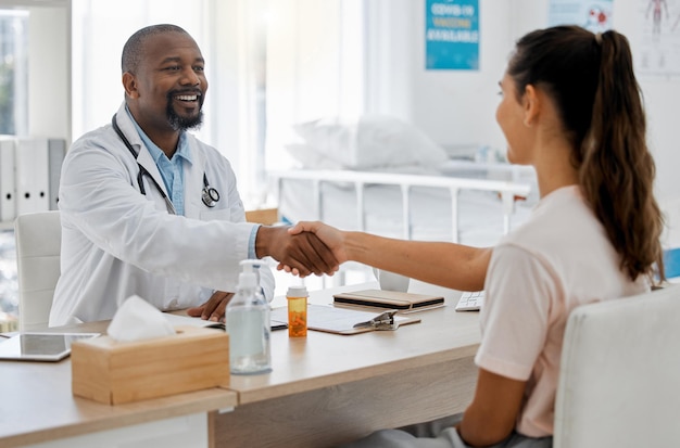 Seguro de salud y apretón de manos entre un médico y un paciente consultando en una oficina discutiendo un plan de tratamiento Mujer feliz sonriendo satisfecha con el consejo experto de un profesional de la salud