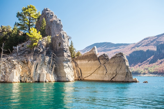 Sehen Sie die Landschaft des Sees mit türkisfarbenem Wasser und scharfen Steinfelsen an.