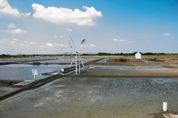 Sehen Sie sich die Landschaft der Salzzucht und der Windkraftanlage mit Wolkenhimmel im Freien in Samut Sakhon und Samut Songkhram Thailand an