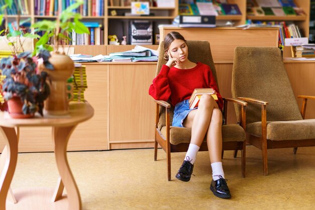 Foto sehen sie sich die wunderschöne junge frau mit einem interessanten buch in den händen an, das sie liest