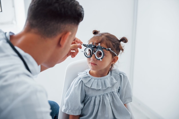 Sehkraft testen. Junge Augenärztin ist mit kleiner weiblicher Besucherin in der Klinik.