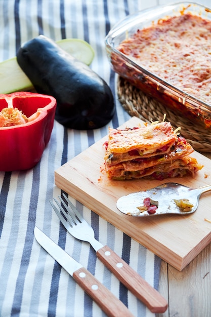 Sehr geschmackvolle selbst gemachte vegetarische Lasagne mit Aubergine und Tomaten, Soße Bechamel auf dem Holztisch.