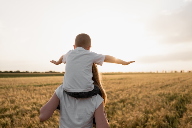 Sehr glückliche Familie von Mutter und Sohn, die Spaß im Freien bei Sommersonnenuntergang haben