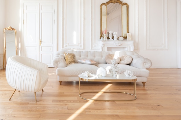 Sehr helles Luxus-Interieur im Barockstil des großen Wohnzimmers. Weiße Wände mit tollem Stuck verziert. Apartment im königlichen Stil mit schicken Möbeln mit Goldelementen